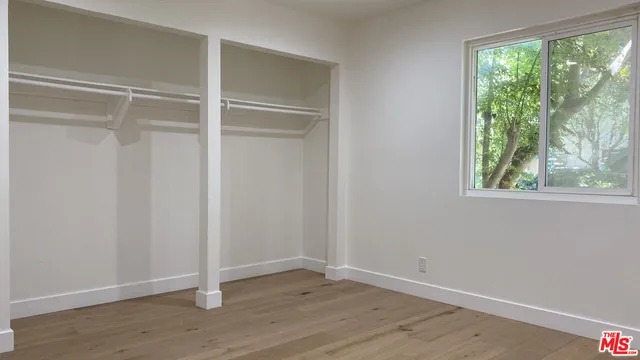 a view of an empty room with wooden floor and window