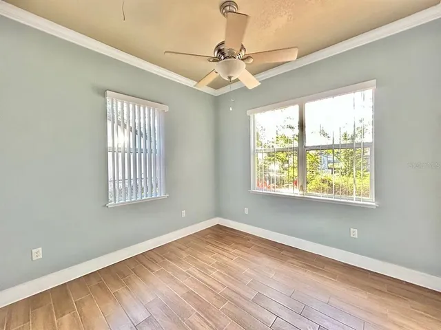 a view of an empty room with wooden floor and a window