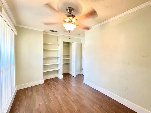 a view of a room with wooden floor and ceiling fan