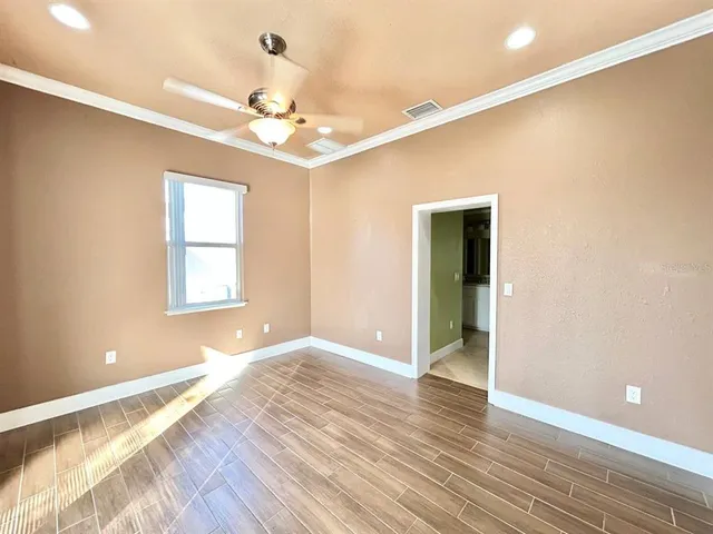 a view of an empty room with wooden floor and a window