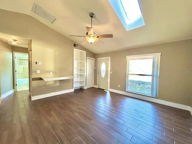 a view of an empty room with window and wooden floor
