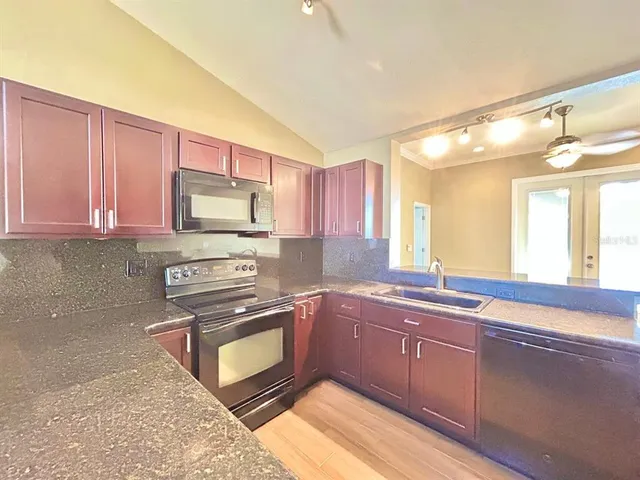 a kitchen with granite countertop a sink cabinets and stainless steel appliances