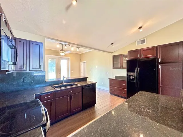 a kitchen with stainless steel appliances granite countertop wooden cabinets a refrigerator and wooden cabinets