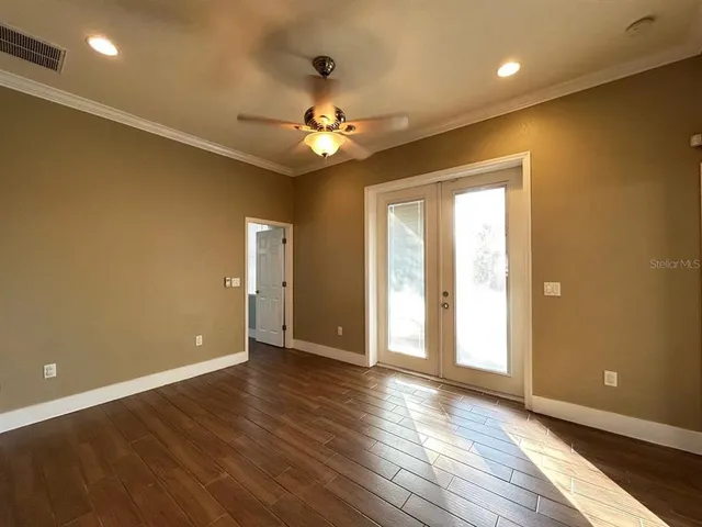 a view of an empty room with window and wooden floor