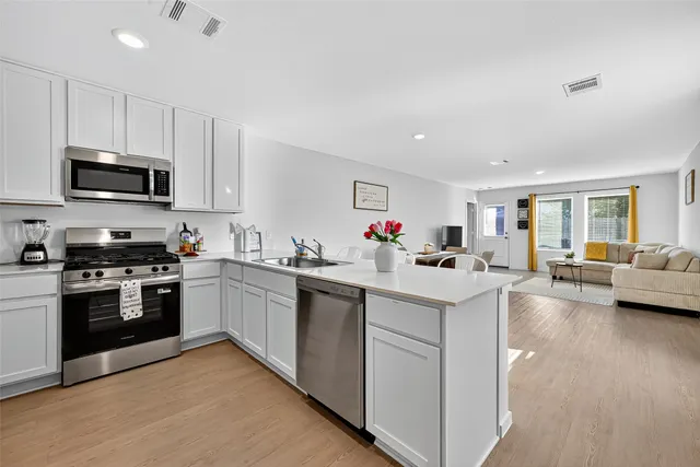 a kitchen with stainless steel appliances granite countertop a refrigerator a sink a stove a microwave and island