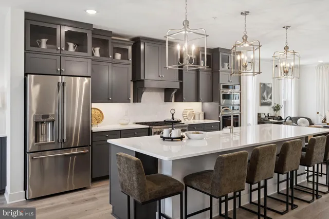 a kitchen with stainless steel appliances granite countertop a dining table chairs refrigerator and sink