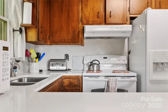 a kitchen with stainless steel appliances granite countertop a sink a stove and a refrigerator