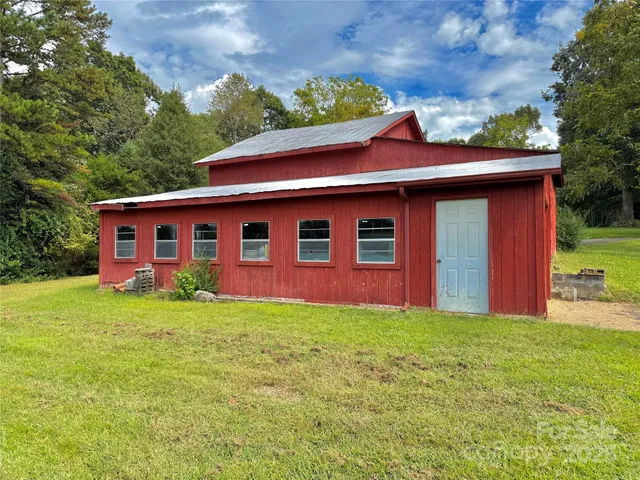 a view of a yard in front of a house with plants and large tree