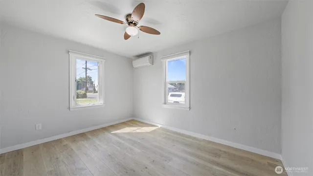 a view of empty room with wooden floor and fan