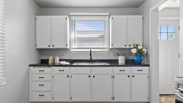 a kitchen with granite countertop a white cabinets and window