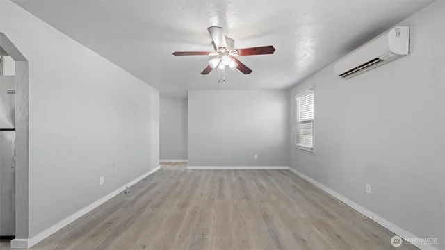an empty room with windows and fan