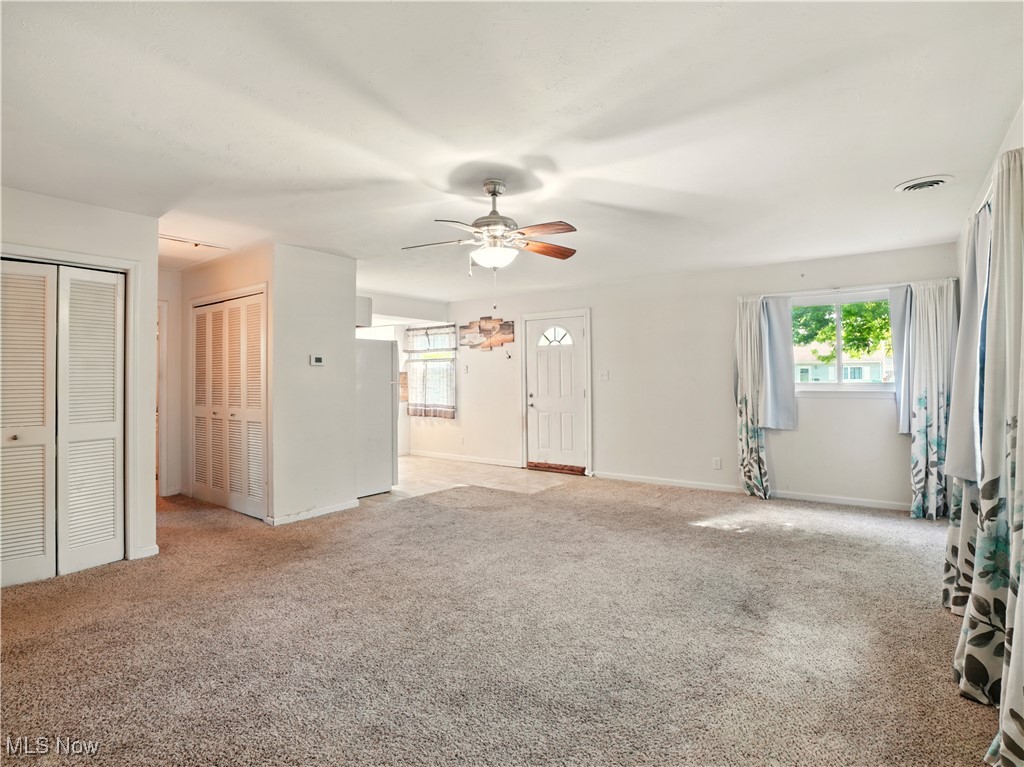 1942 Benjamin Road Madison, OH 44057 - Photo 9 of 29 Unfurnished living room with light carpet, a ceiling fan, and baseboards