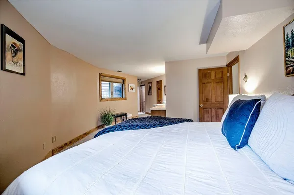 a bedroom with a large bed wooden floor and window