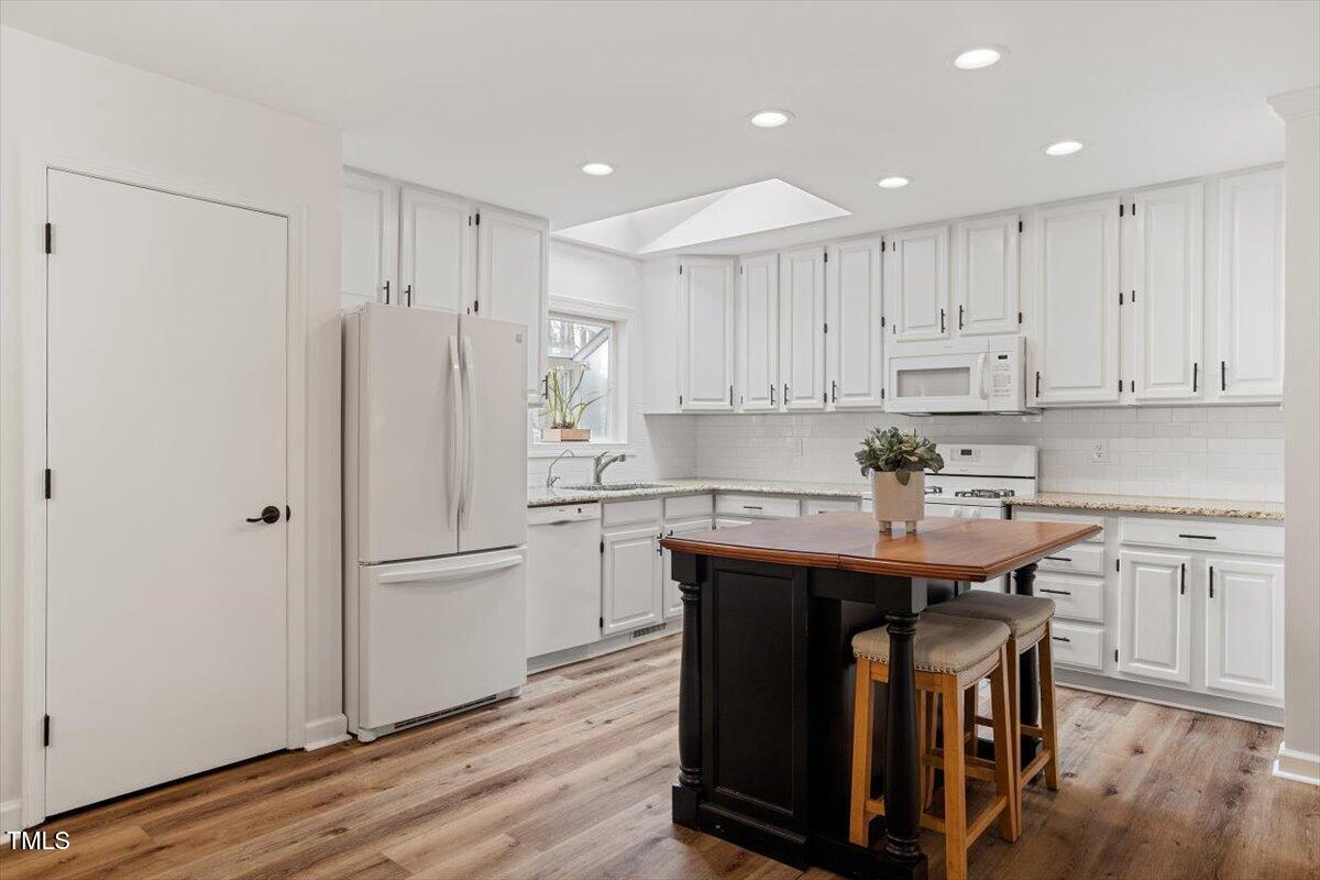 1203 Brookgreen Drive Cary, NC 27511 - Photo 12 of 46 a kitchen with stainless steel appliances granite countertop a table chairs refrigerator and cabinets