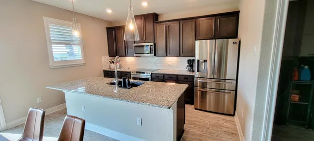 a kitchen with kitchen island a counter top space cabinets stainless steel appliances and a window
