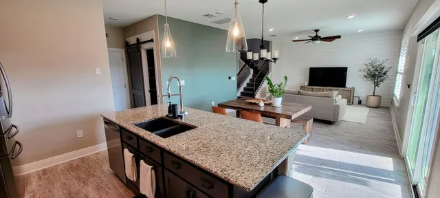 a living room with furniture kitchen view and a wooden floor