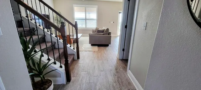 a hallway with wooden floor and stairs