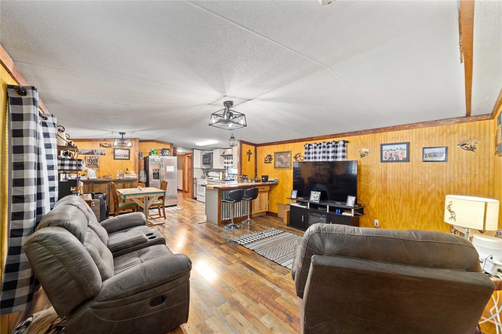 4991 Thunderbird Drive May, TX 76857 - Photo 13 of 34 Living area featuring lofted ceiling, wooden walls, light wood-type flooring, and indoor bar