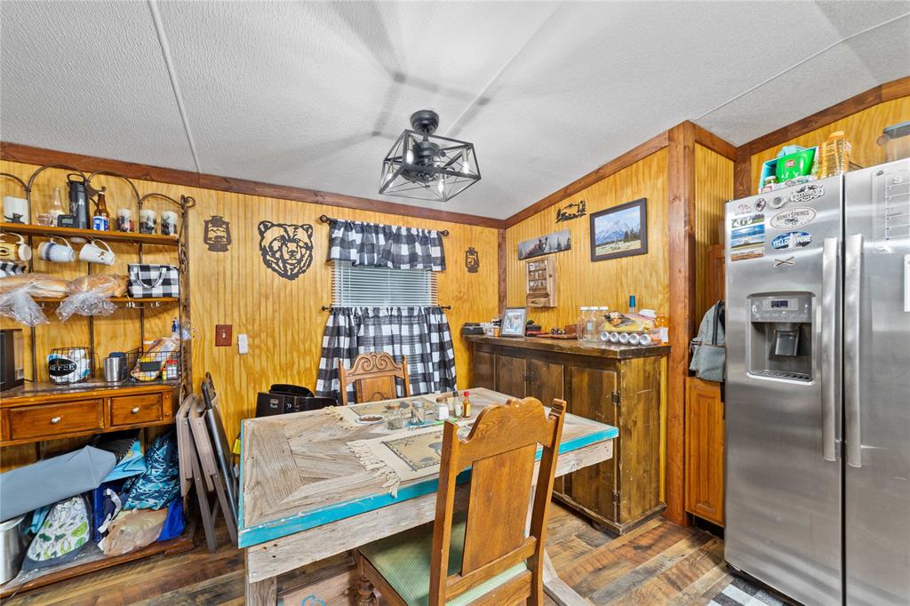 4991 Thunderbird Drive May, TX 76857 - Photo 14 of 34 Dining space featuring a textured ceiling, wood walls, and wood finished floors