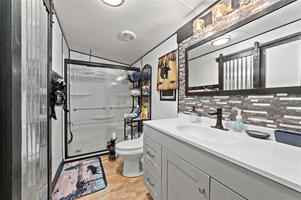 4991 Thunderbird Drive May, TX 76857 - Photo 17 of 34 Bathroom with a shower stall, vanity, tasteful backsplash, toilet, and vaulted ceiling