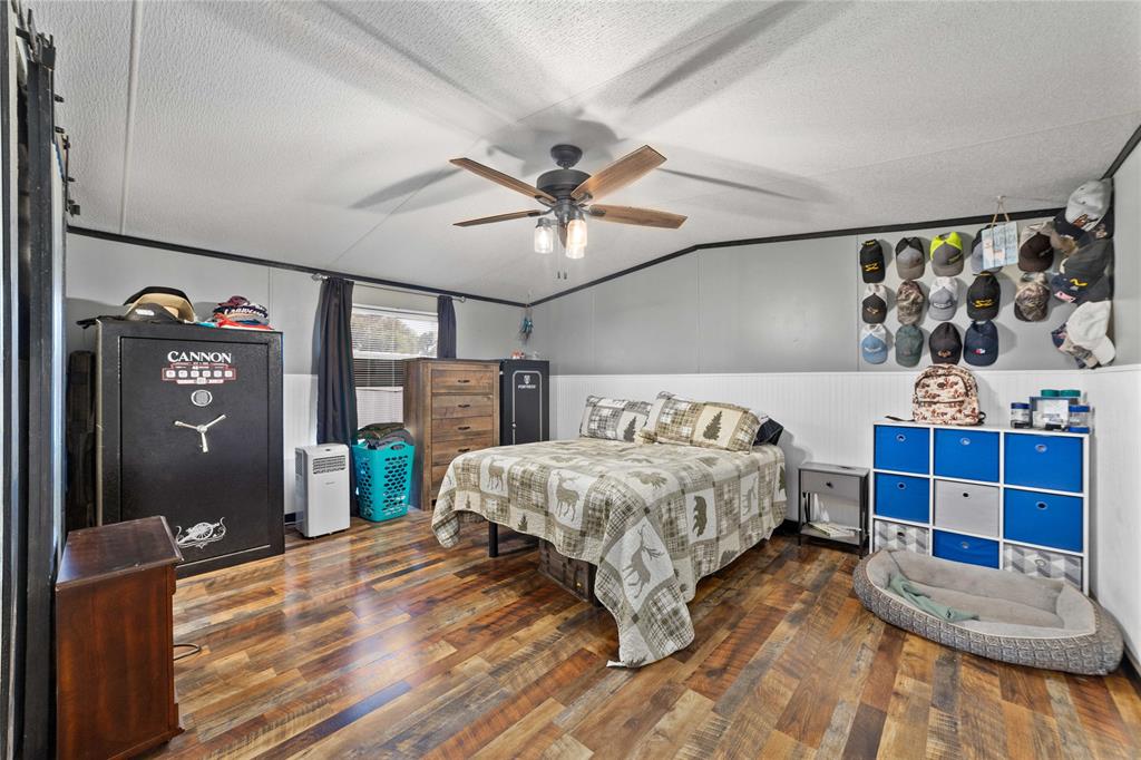 4991 Thunderbird Drive May, TX 76857 - Photo 19 of 34 Bedroom with a wainscoted wall, wood-type flooring, a ceiling fan, a textured ceiling, and lofted ceiling