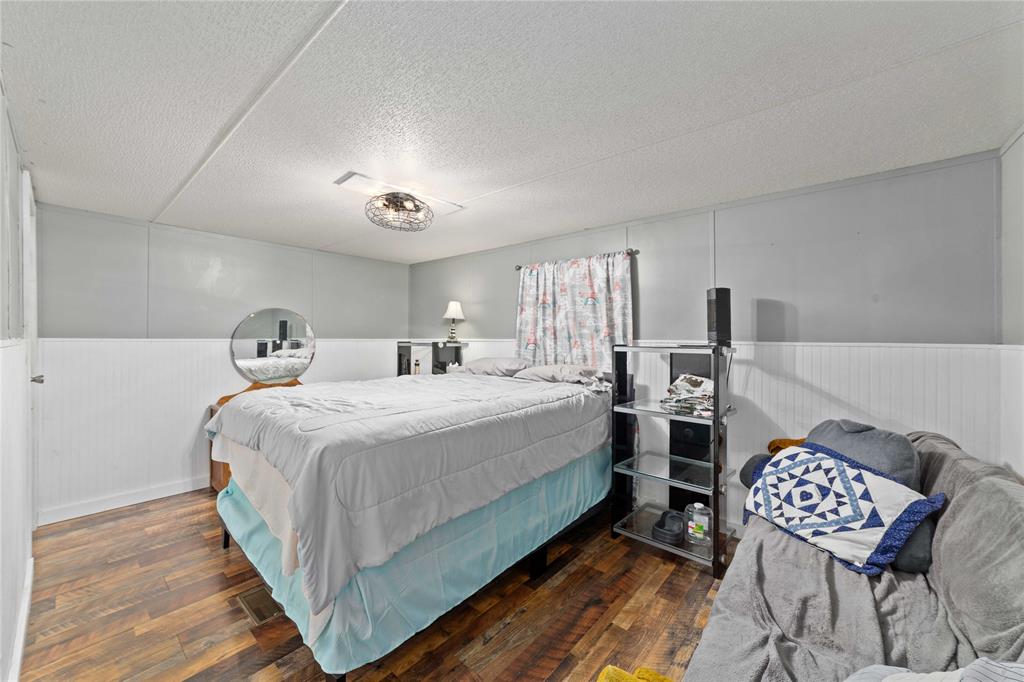 4991 Thunderbird Drive May, TX 76857 - Photo 20 of 34 Bedroom featuring wood-type flooring, a textured ceiling, and wainscoting