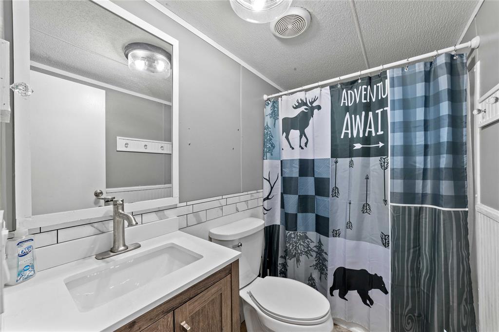 4991 Thunderbird Drive May, TX 76857 - Photo 21 of 34 Full bathroom featuring a textured ceiling, a shower with curtain, visible vents, toilet, and vanity
