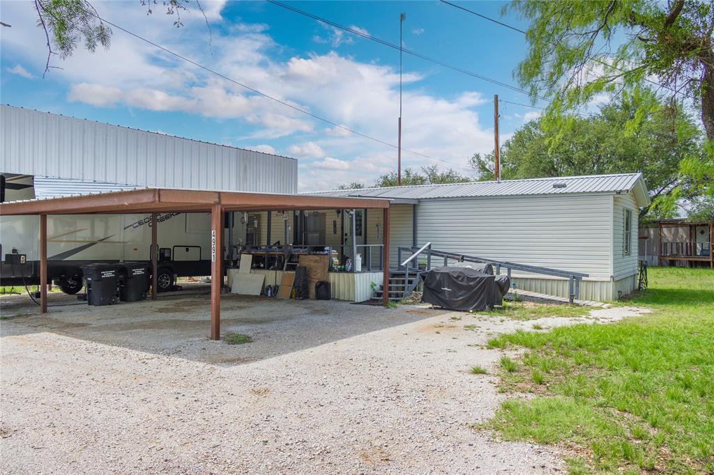 4991 Thunderbird Drive May, TX 76857 - Photo 28 of 34 Back of property with metal roof, dirt driveway, and an attached carport