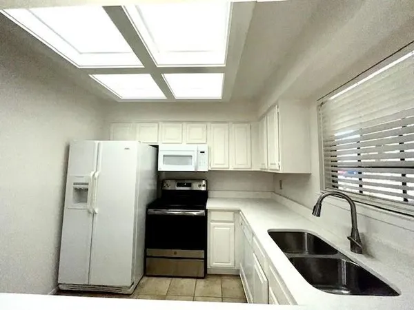 a kitchen with a refrigerator sink and white cabinets