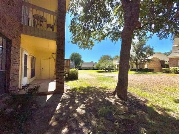 a view of a big building next to a big yard and large trees
