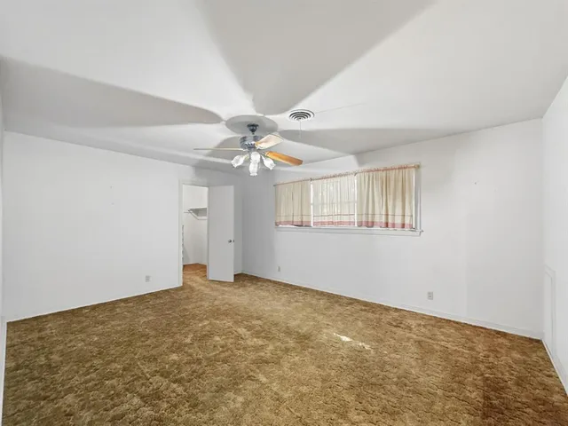 a view of an empty room with chandelier fan and wooden floor