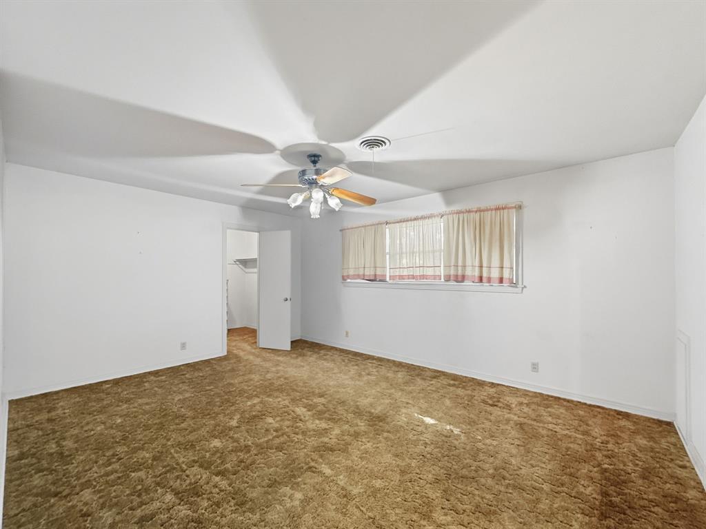 817 South Rusk Street Gainesville, TX 76240 - Photo 6 of 25 a view of an empty room with chandelier fan and wooden floor