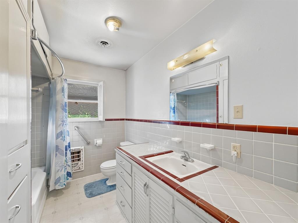 817 South Rusk Street Gainesville, TX 76240 - Photo 7 of 25 a bathroom with a sink a toilet a mirror and shower