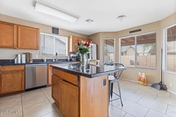 a kitchen with stainless steel appliances granite countertop a stove a sink a refrigerator a microwave oven and a dining table with wooden floor