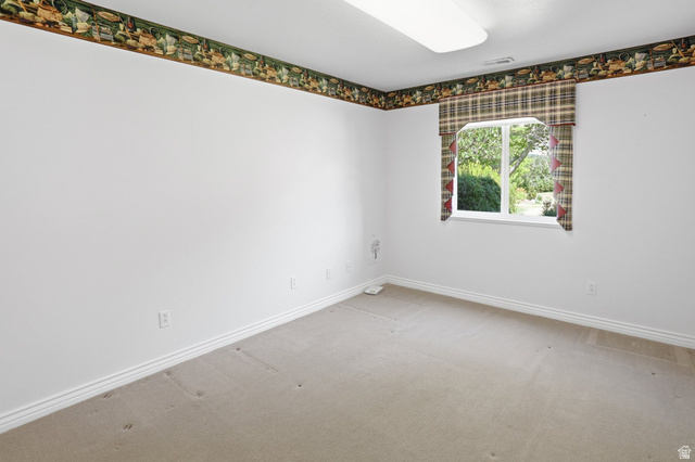 2190 750 West Perry, UT 84302 - Photo 27 of 42 Room featuring a single window with a plaid valance, light beige carpeting, white walls, white baseboards, and a decorative wallpaper border