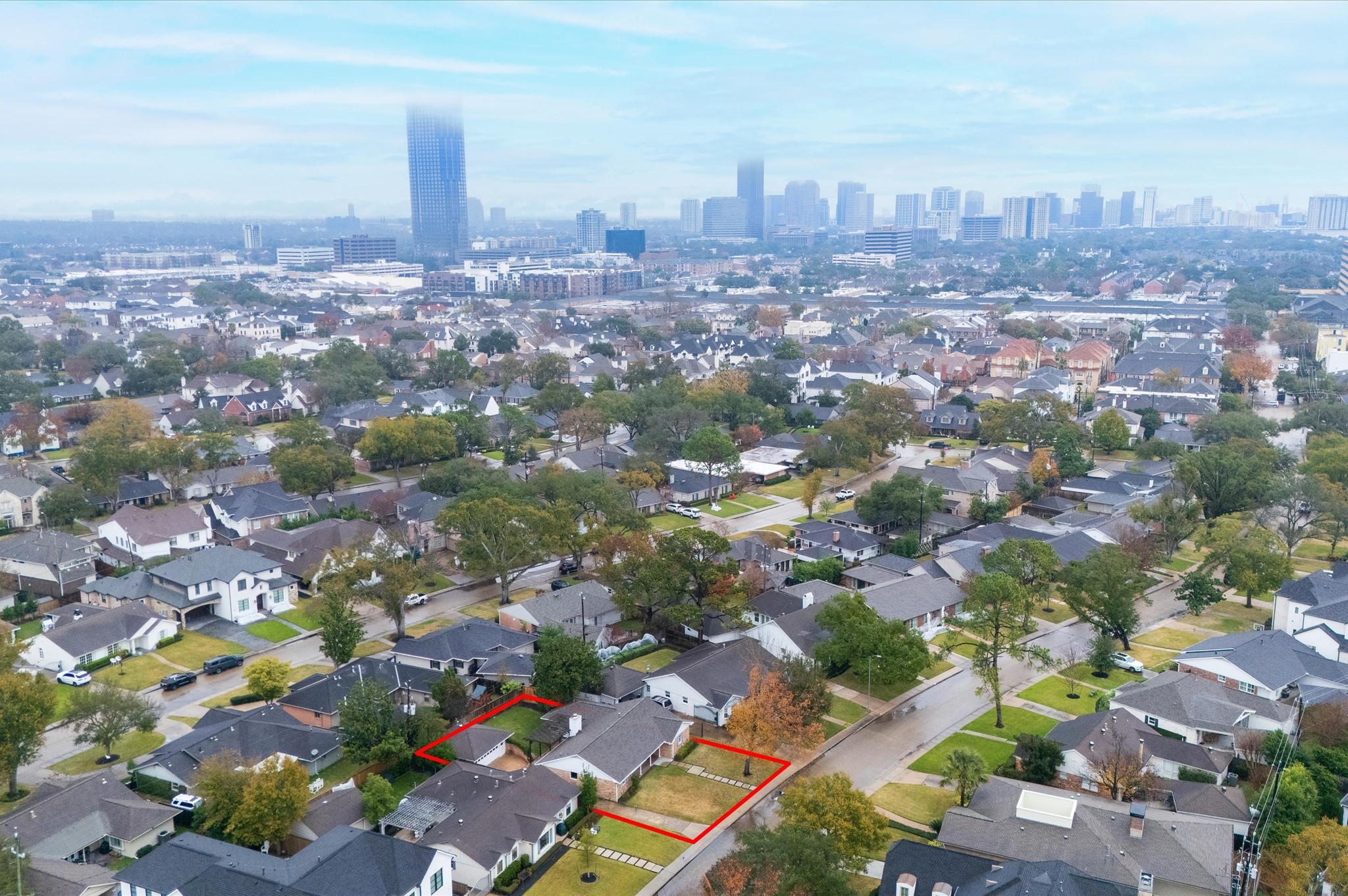 6158 Burgoyne Road Houston, TX 77057 - Photo 36 of 39 This aerial photo showcases Briargrove's neighborhood with tree-lined streets and well-kept homes. The property outlined in red is centrally located, offering easy access to a vibrant city skyline in the background. Ideal for buyers seeking a blend of residential comfort and urban convenience.