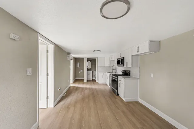 a kitchen with granite countertop a stove top oven a sink dishwasher and a refrigerator with wooden floor