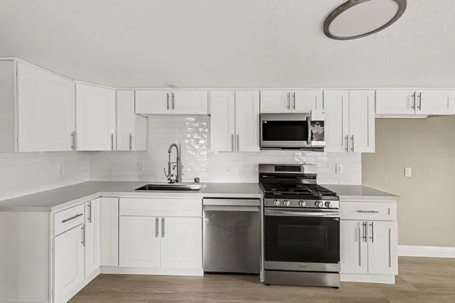 a kitchen with white cabinets stainless steel appliances and sink