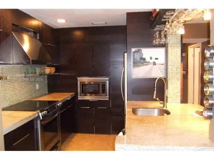 a kitchen with granite countertop a stove a sink and a refrigerator