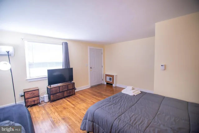 a bedroom with a bed tv and wooden floor
