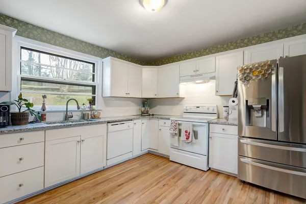 a kitchen with granite countertop white cabinets and white stainless steel appliances