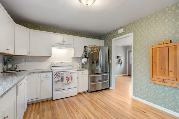 a kitchen with wooden floors and white appliances