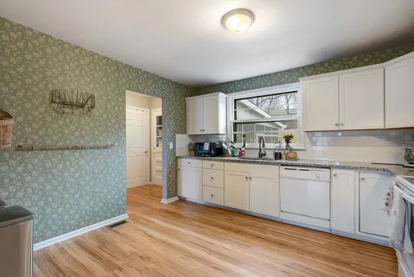 a kitchen with granite countertop wooden floors white cabinets and wooden floor