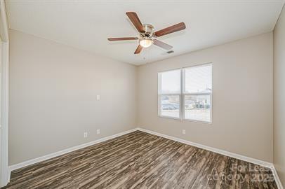 238 Hoskins Mill Lane, Unit D Charlotte, NC 28208 - Photo 4 of 13 an empty room with wooden floor fan and windows