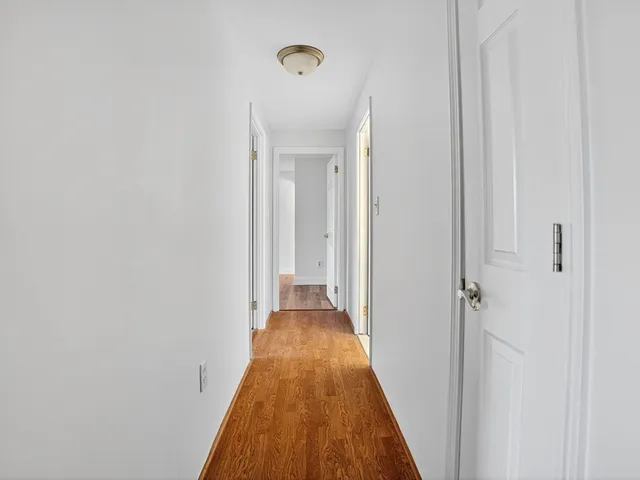 a view of a hallway with wooden floor and a bathroom