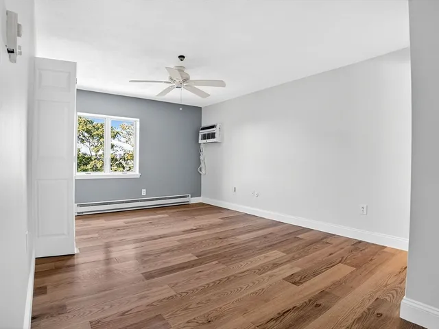 an empty room with wooden floor chandelier fan and windows