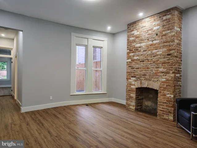 an empty room with wooden floor fireplace and windows