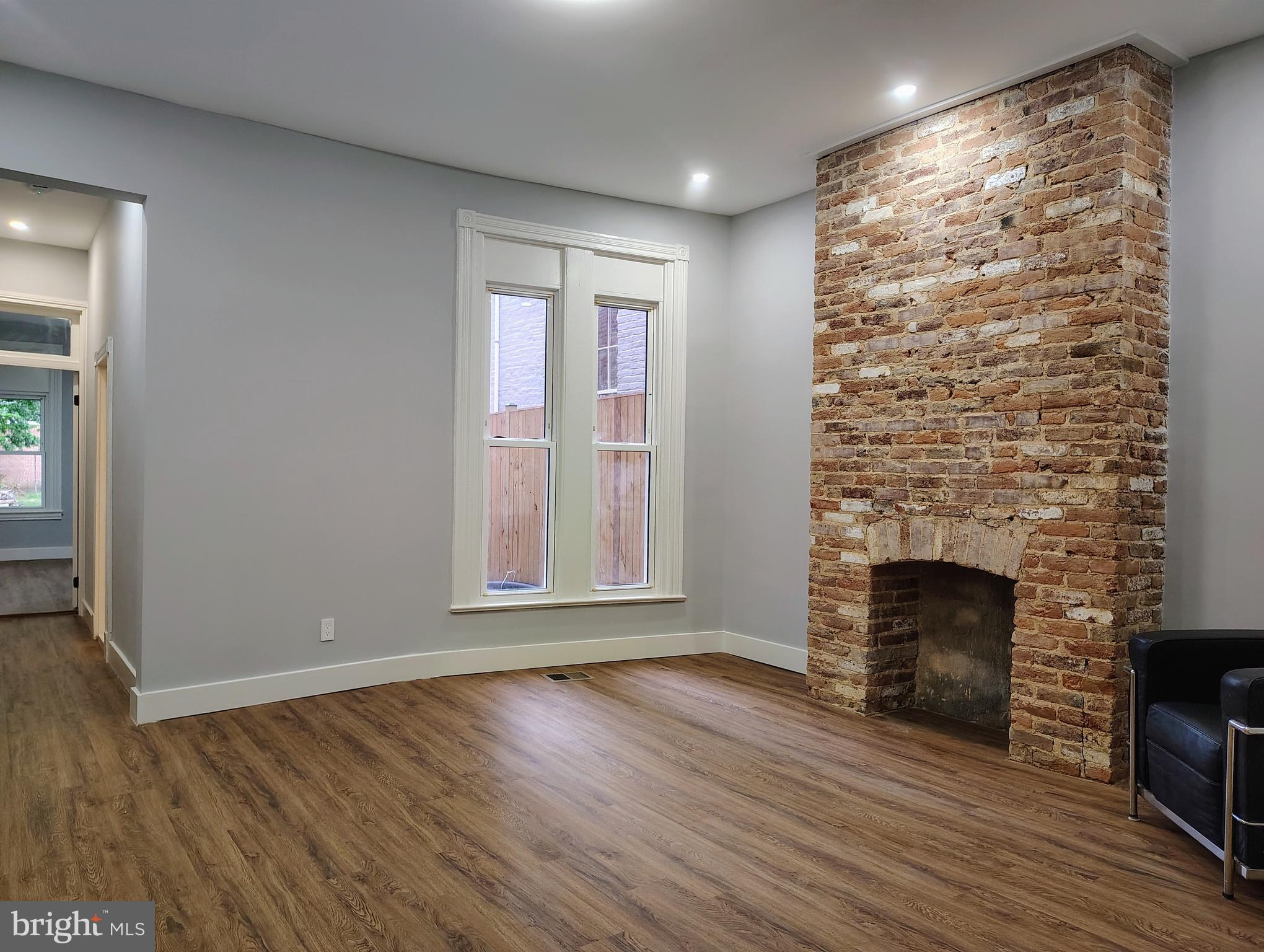 an empty room with wooden floor fireplace and windows
