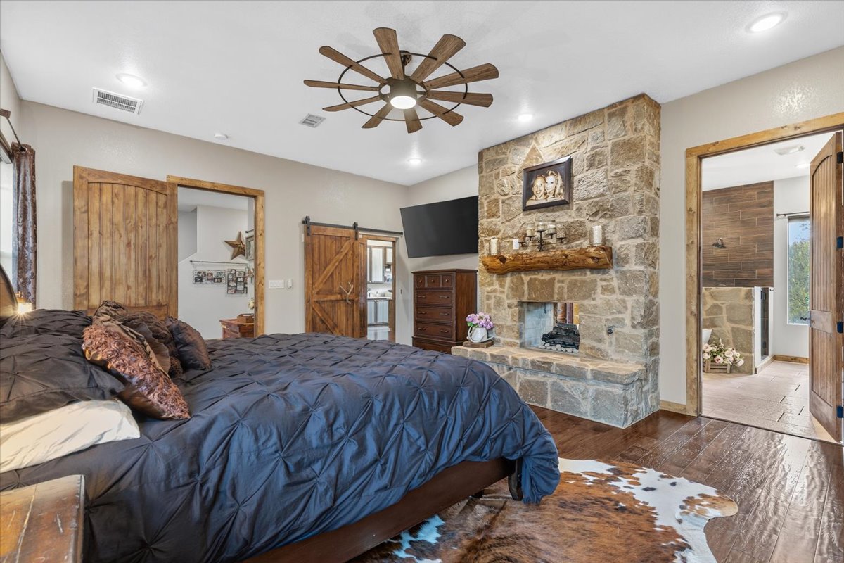 175 Wilson Road Elgin, TX 78621 - Photo 14 of 40 Welcome to the primary suite! It’s huge, but it still feels so cozy and private. It easily accommodates a king-sized bedroom set with room to spare, and that fireplace goes through right into the ensuite bathroom!