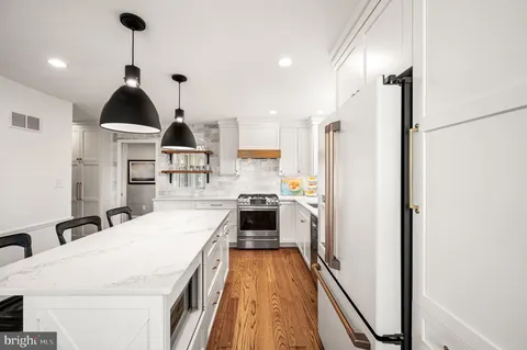 a kitchen with stainless steel appliances a stove a refrigerator and a view of living room